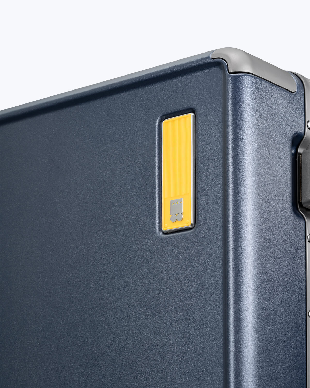 Hegent Carry On 20" navy suitcase close-up of yellow signature logo plate